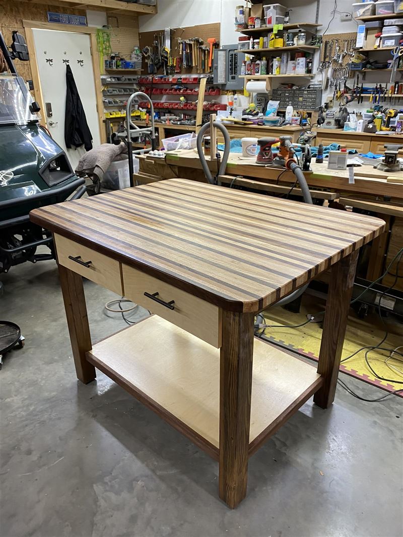 Striped hardwood kitchen island with two drawers and a lower shelf in a home workshop