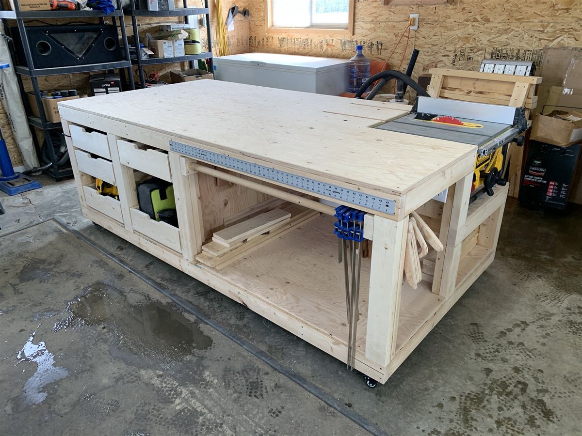 Large rolling workbench with drawers and a built-in table saw in a home garage shop